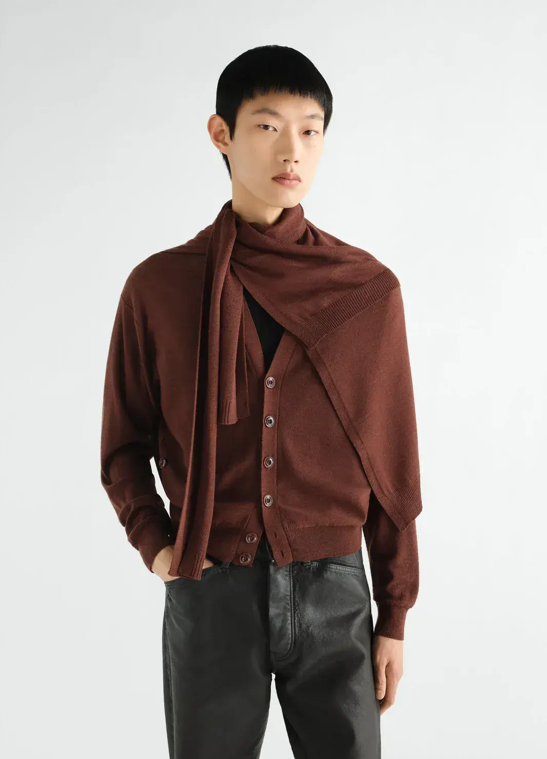 A model in a brown cardigan with a knitted scarf over one shoulder